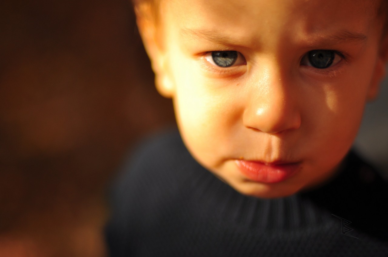 A close-up child portrait in warm light with sharp eyes and a softly blurred background.