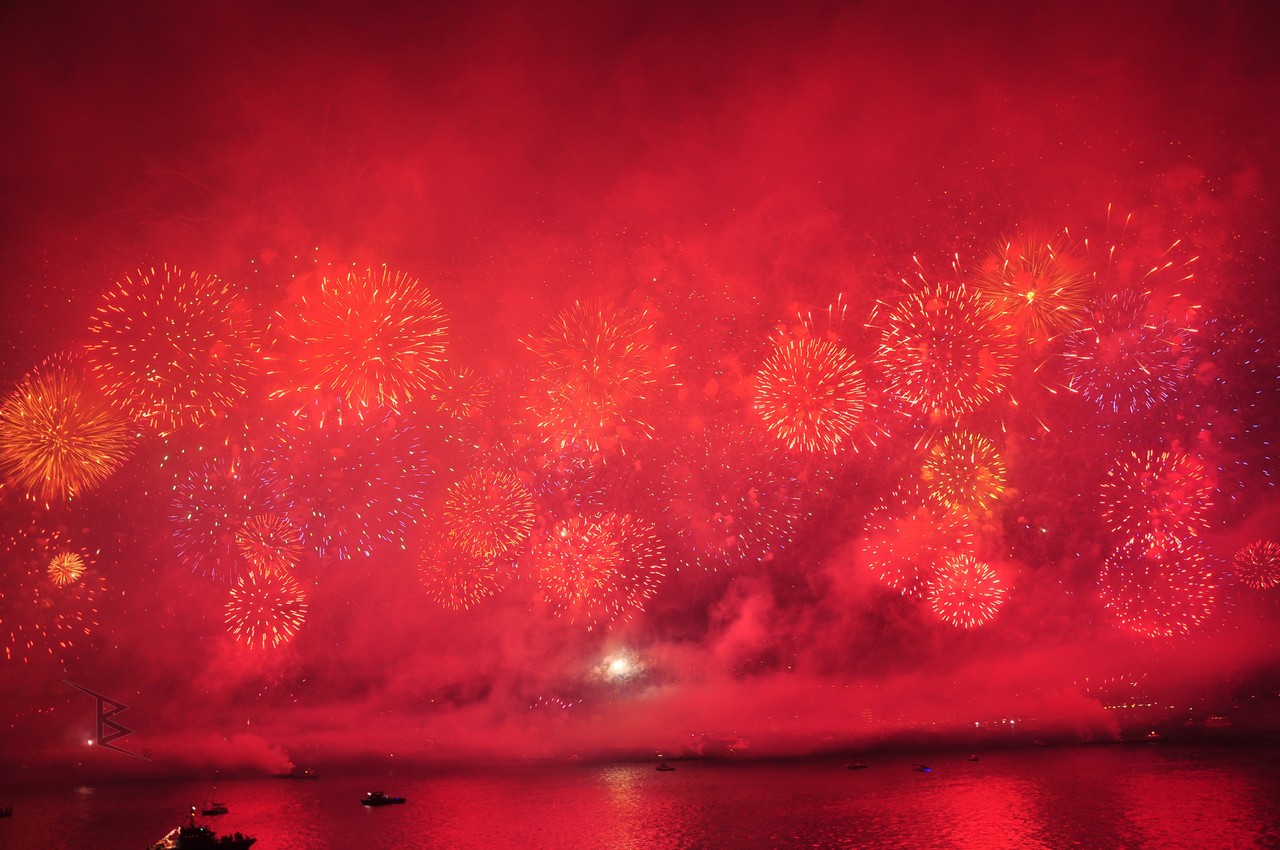 Istanbul Bosphorus fireworks spread red, gold and blue light through smoke above the water.