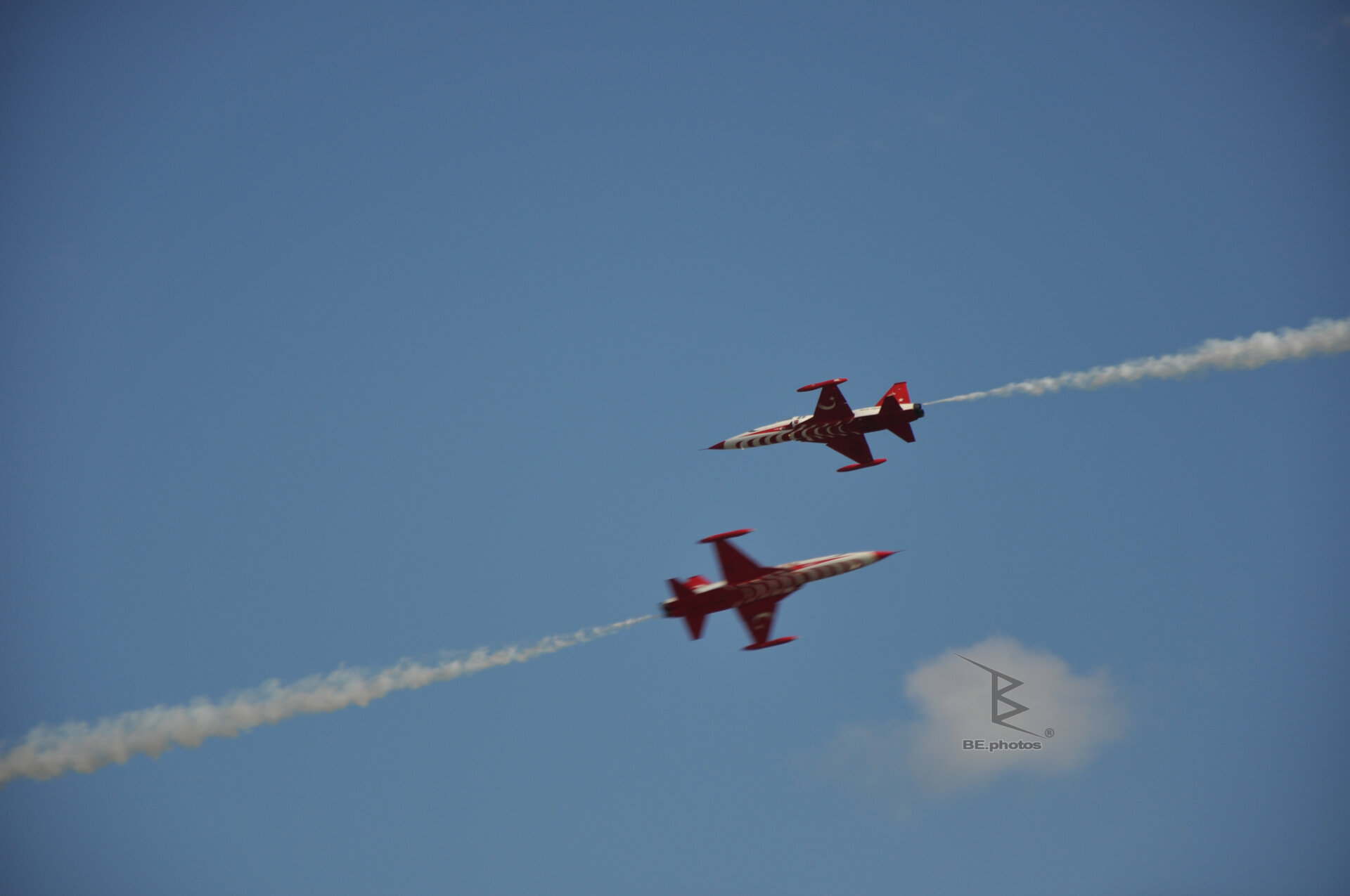 Two Turkish Stars jets passing through the blue sky with a white smoke trail.