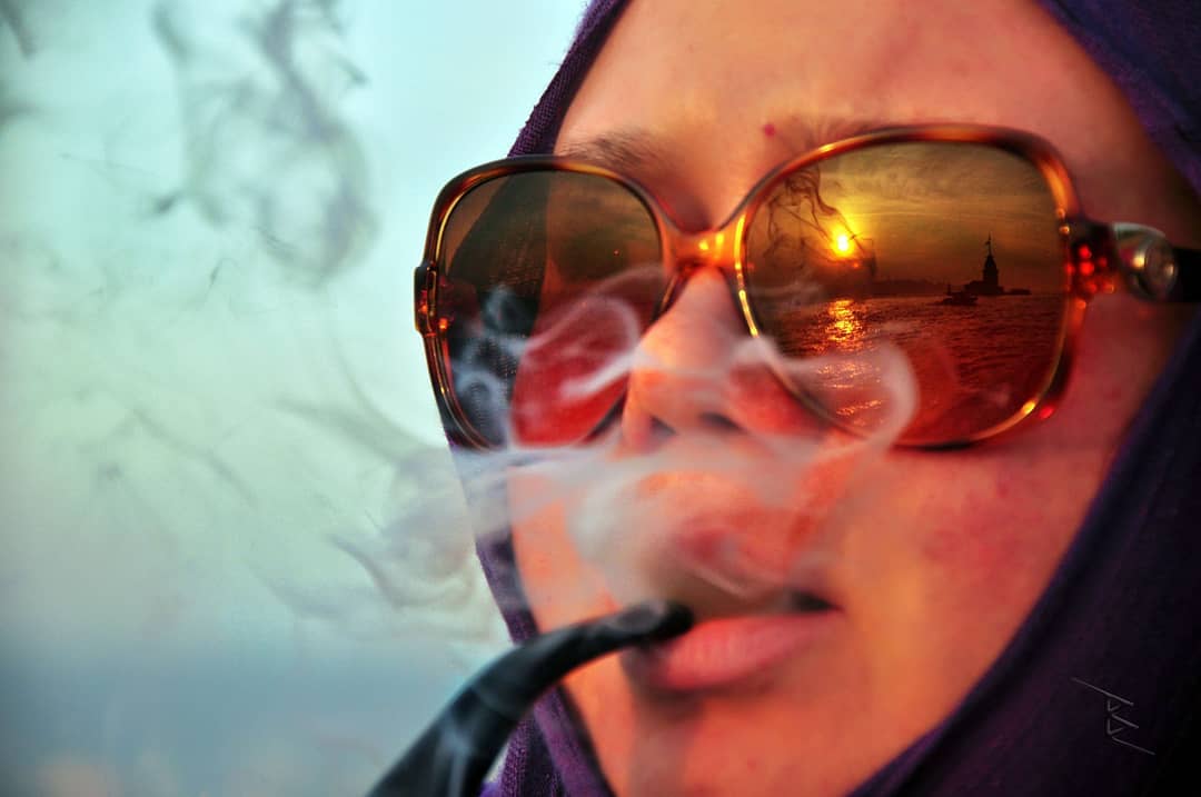 A Maiden's Tower Reflection in Her Sunglasses 1 A close portrait of a woman with a pipe and sunglasses reflecting Istanbul's Maiden's Tower at sunset.