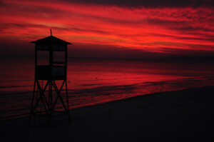 A lifeguard tower at sunset silhouetted against a red sky and dark sea in Florya.