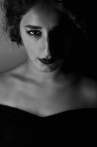 The light she left in the dark, a low-light black and white portrait of a woman with one eye and half her face emerging from shadow.